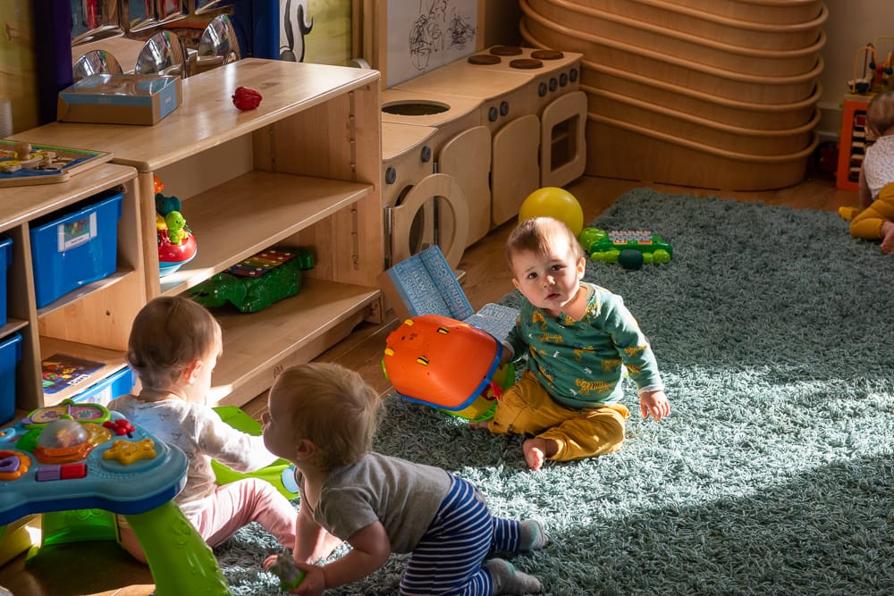 Child plays with toys on the floor of nursery