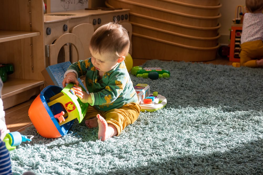 Child plays with toys on the floor of nursery